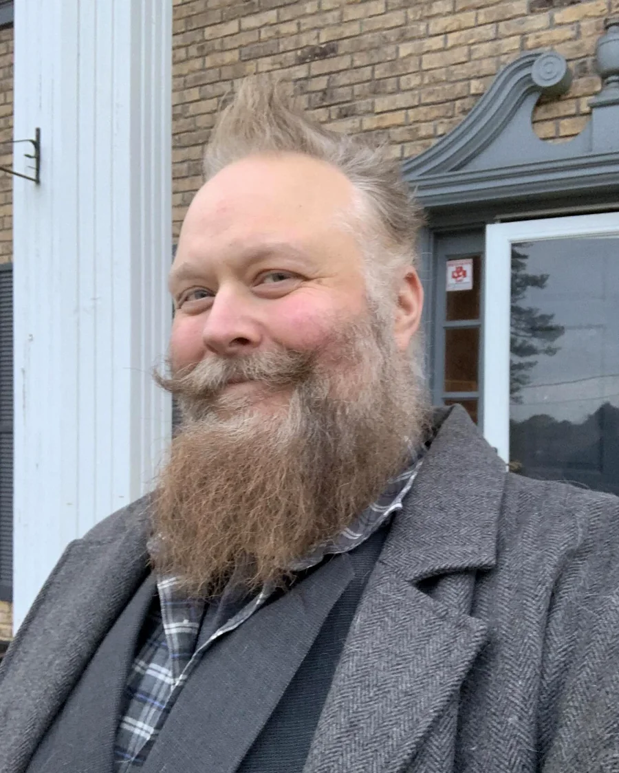 Joel Hallet, photographed outdoors in a tweed overcoat and waistcoat